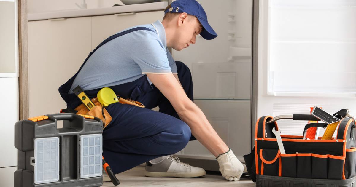 Monteur repareert koelkast in de keuken